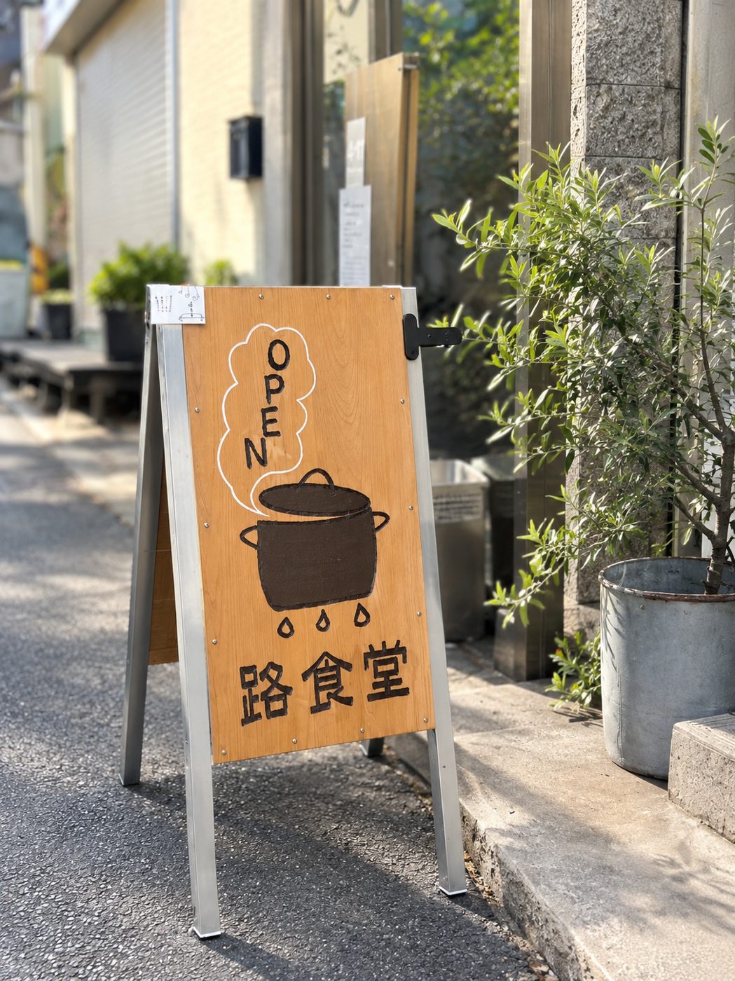 路地に出ている路食堂の看板。湯気の立つお鍋の絵とOPENの文字